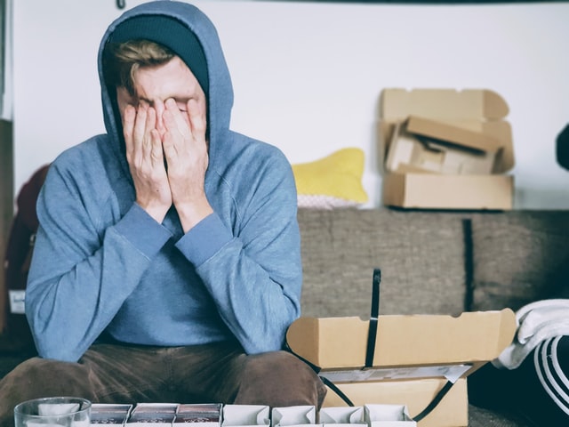 Caucasian man with his hands in front of his face, looking defeated.