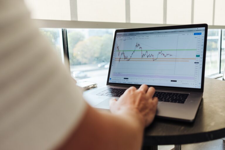 Man sitting at a table with a laptop displaying a trend chart