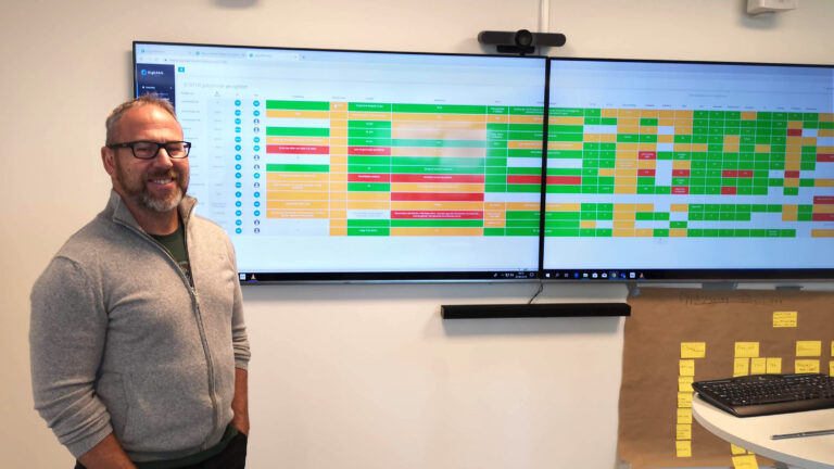 Terje Nøttveit standing in front of dual screen setup with DigiLEAN showing project management board